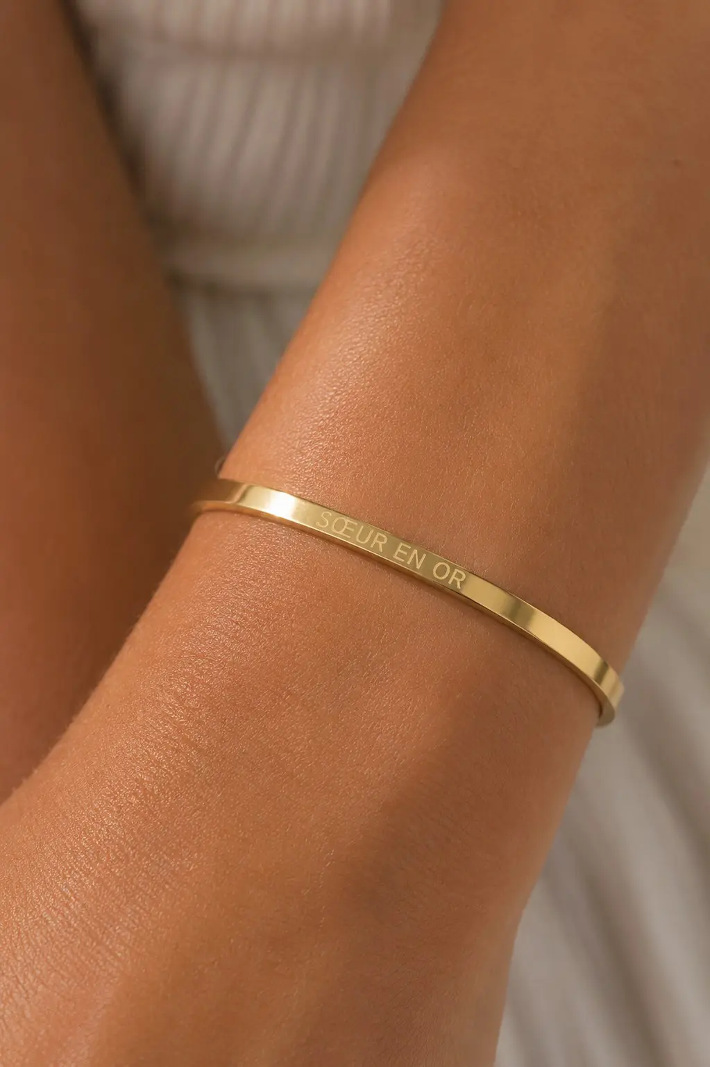 Bracelet message sœur en acier inoxydable doré avec gravure “Sœur en or” porté au poignet femme